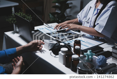 Two asian women doctors discuss meeting doctor's office medical clinic looking x-ray film consulting patient disease. Asian medical lab young women talking together discussing healthcare teamwork Two asian women doctors discuss meeting doctor's office medical clinic looking x-ray film consulting patient disease. Asian medical lab young women talking together discussing healthcare teamwork 141274862