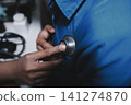 Doctor use stethoscope, checking up heart beat, auscultation in doctor office at hospital. Patient worker has to get medical checkup every year for her health or 141274870