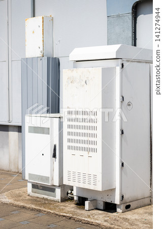 Weathered outdoor electrical cabinets against industrial wall Weathered outdoor electrical cabinets against industrial wall 141274944