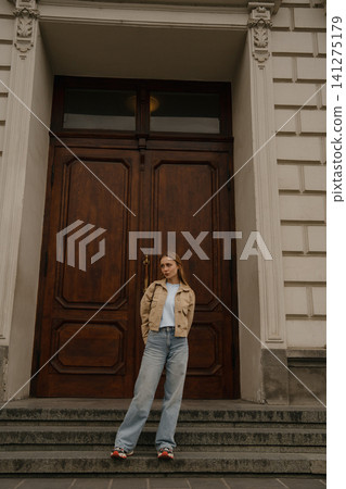 Girl with freckles stands in front of a large wooden door at a historical building during the day Girl with freckles stands in front of a large wooden door at a historical building during the day 141275179