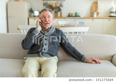 Happy middle aged senior man talking on smartphone with family friends. Older mature grandfather with cell phone talking with grown up children, resting at home. Older generation modern tech usage Happy middle aged senior man talking on smartphone with family friends. Older mature grandfather with cell phone talking with grown up children, resting at home. Older generation modern tech usage 141275684
