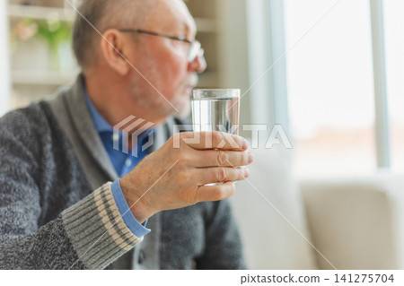Senior man holding glass drinking fresh water at home. Mature old senior thirsty grandfather takes care of his health. Healthcare water balance. Elderly healthy lifestyle Senior man holding glass drinking fresh water at home. Mature old senior thirsty grandfather takes care of his health. Healthcare water balance. Elderly healthy lifestyle 141275704
