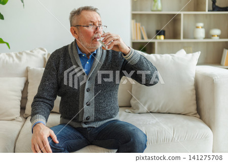 Senior man holding glass drinking fresh water at home. Mature old senior thirsty grandfather takes care of his health. Healthcare water balance. Elderly healthy lifestyle Senior man holding glass drinking fresh water at home. Mature old senior thirsty grandfather takes care of his health. Healthcare water balance. Elderly healthy lifestyle 141275708