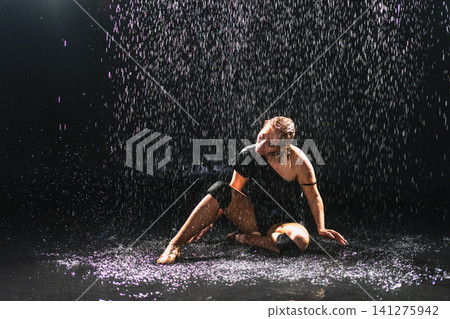 Contemporary woman dancer posing in rain water on black background. Female artist performer dancing with expression. Modern ballerina dancing in darkness. Passion dance in dark. Flexibility balance Contemporary woman dancer posing in rain water on black background. Female artist performer dancing with expression. Modern ballerina dancing in darkness. Passion dance in dark. Flexibility balance 141275942