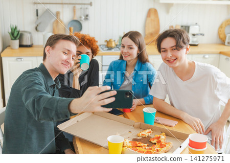 Cheers Funky mood. Happy group of friends make selfie. Man taking photo of friends at party. Group of multiracial young people taking photo on phone. Young people enjoy their company smile have fun Cheers Funky mood. Happy group of friends make selfie. Man taking photo of friends at party. Group of multiracial young people taking photo on phone. Young people enjoy their company smile have fun 141275971