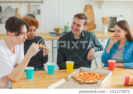 Home party. Overjoyed diverse friends eating ordered pizza for home party. Happy group multiracial young buddies enjoying spending free weekend time together having fun laughing joking communicating 141275973