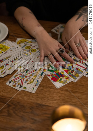 Tarot cards and fortune telling. Soothsayer predicting future with tarot cards. Unrecognizable mysterious fortuneteller holding tarot cards forecasting future for client. Future reading esoteric Tarot cards and fortune telling. Soothsayer predicting future with tarot cards. Unrecognizable mysterious fortuneteller holding tarot cards forecasting future for client. Future reading esoteric 141276016