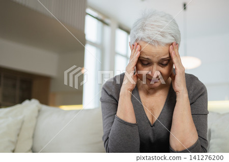 Sad tired ill sick lonely disappointed older senior woman sitting at home alone. Unhappy mature grandmother experiencing grief relative death bad news. Stressed elder lady suffering from loneliness Sad tired ill sick lonely disappointed older senior woman sitting at home alone. Unhappy mature grandmother experiencing grief relative death bad news. Stressed elder lady suffering from loneliness 141276200