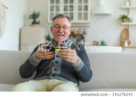 Senior man shopping online holding smartphone paying with credit card. Old grandfather buying on Internet enter credit card details. Online shopping delivery service Older generation modern tech usage Senior man shopping online holding smartphone paying with credit card. Old grandfather buying on Internet enter credit card details. Online shopping delivery service Older generation modern tech usage 141276245
