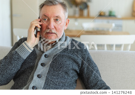 Happy middle aged senior man talking on smartphone with family friends. Older mature grandfather with cell phone talking with grown up children, resting at home. Older generation modern tech usage Happy middle aged senior man talking on smartphone with family friends. Older mature grandfather with cell phone talking with grown up children, resting at home. Older generation modern tech usage 141276248