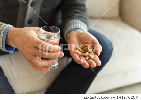 Hands with pills. Senior man hands holding medical pill and glass of water. Mature old senior grandfather taking medication cure pills vitamin. Age prescription medicine healthcare therapy concept Hands with pills. Senior man hands holding medical pill and glass of water. Mature old senior grandfather taking medication cure pills vitamin. Age prescription medicine healthcare therapy concept 141276267