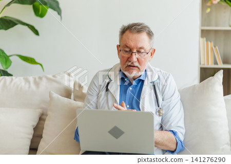 Senior man doctor with laptop talk on video call have consultation with patient. Professional senior mature healthcare expert examining patient online. Medicine healthcare medical checkup Senior man doctor with laptop talk on video call have consultation with patient. Professional senior mature healthcare expert examining patient online. Medicine healthcare medical checkup 141276290