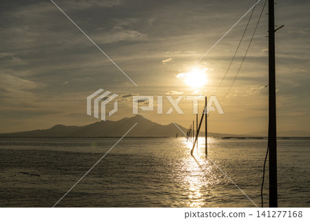 傍晚時分,海面上的電線桿在燈光的背景下勾勒出清晰的輪廓。 傍晚時分,海面上的電線桿在燈光的背景下勾勒出清晰的輪廓。 141277168