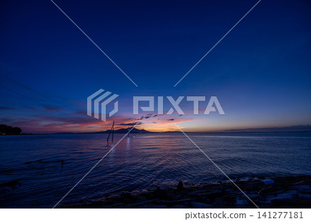 The sea at dusk, lined with power poles in the ocean. The sea at dusk, lined with power poles in the ocean. 141277181