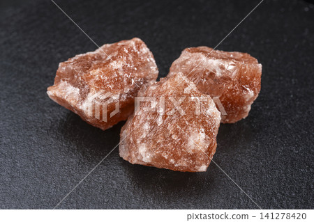 A collection of red Himalayan rock salt against a black background. A collection of red Himalayan rock salt against a black background. 141278420