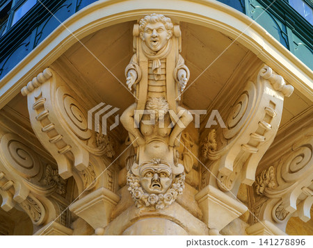 Corner sculpture of Atlas seated on the shoulders of Carryatis, supporting the bay window of the Palace of the Grand Master covered balconies in Valetta, Malta Corner sculpture of Atlas seated on the shoulders of Carryatis, supporting the bay window of the Palace of the Grand Master covered balconies in Valetta, Malta 141278896