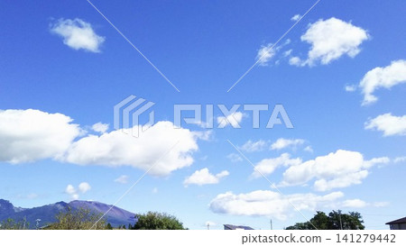A peaceful townscape spreads out at the foot of Mount Asama, against a clear blue sky with white clouds floating gently. 141279442