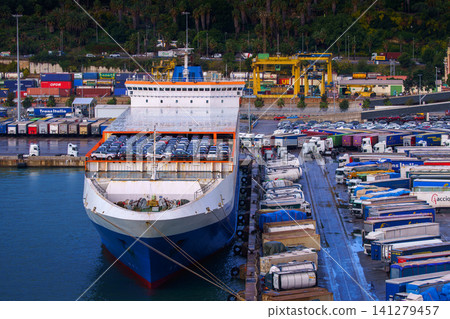 Barcelona, Spain - Nov 9 2018, panoramic view of the port of Barcelona with a moored cargo ship loaded with cars, trucks with trailers parked on the pier, at evening, Barcelona, Spain Barcelona, Spain - Nov 9 2018, panoramic view of the port of Barcelona with a moored cargo ship loaded with cars, trucks with trailers parked on the pier, at evening, Barcelona, Spain 141279457