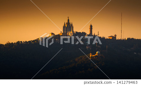 Barcelona, Spain - Nov 9 2018, panoramic view of Mount Tibidabo with Temple of Sacred Heart of Jesus, Expiatori del Sagrat Cor and the Ferris wheel at the top, at evening at sunset, Barcelona, Spain Barcelona, Spain - Nov 9 2018, panoramic view of Mount Tibidabo with Temple of Sacred Heart of Jesus, Expiatori del Sagrat Cor and the Ferris wheel at the top, at evening at sunset, Barcelona, Spain 141279463