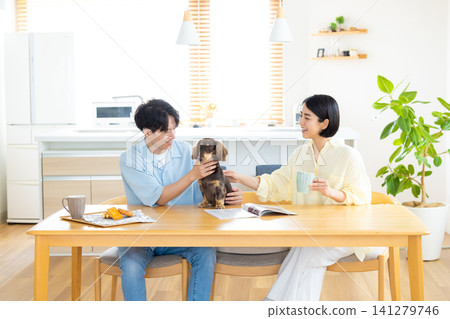 Family life with a dog: A couple spending time with their beloved dog in the living room. Family life with a dog: A couple spending time with their beloved dog in the living room. 141279746