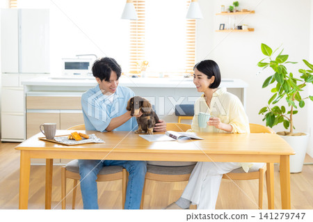 Family life with a dog: A couple spending time with their beloved dog in the living room. Family life with a dog: A couple spending time with their beloved dog in the living room. 141279747