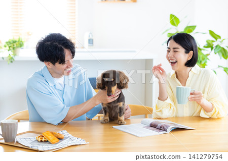 Family life with a dog: A couple spending time with their beloved dog in the living room. Family life with a dog: A couple spending time with their beloved dog in the living room. 141279754