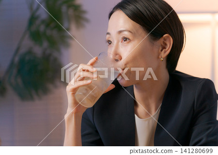 A woman smiling while drinking alcohol A woman smiling while drinking alcohol 141280699
