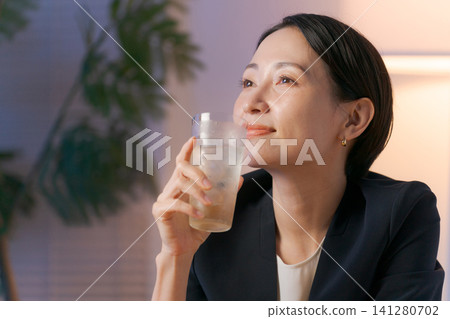 A woman smiling while drinking alcohol A woman smiling while drinking alcohol 141280702