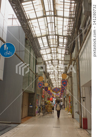 The shopping arcade retains a retro Showa-era atmosphere, and shoppers walk through it, creating an everyday scene. 141280732