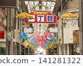 The entrance to a retro Showa-era shopping street, adorned with colorful flags and a "Fashion Street" sign. 141281322