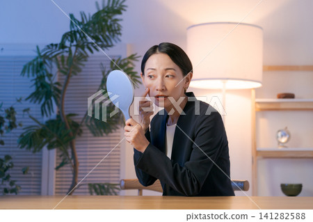 一個穿著西裝的女人在夜裡照鏡子 一個穿著西裝的女人在夜裡照鏡子 141282588