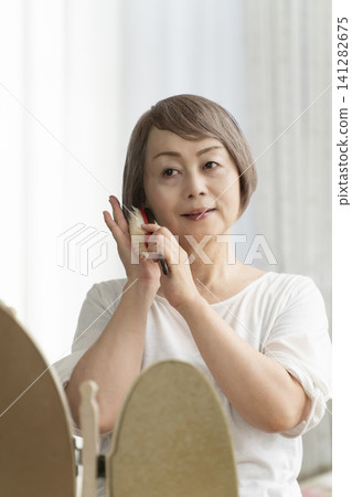 一位老婦人正在用梳子梳理頭髮。 一位老婦人正在用梳子梳理頭髮。 141282675
