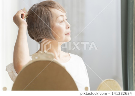 一位老婦人正在用梳子梳理頭髮。 一位老婦人正在用梳子梳理頭髮。 141282684