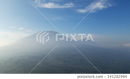 Misty mountain peaks rise above lush green forests 141282994