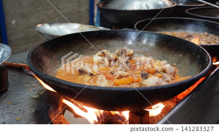 Chicken karahi simmering in a large wok over an open flame, street food Chicken karahi simmering in a large wok over an open flame, street food 141283327