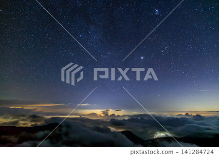 A late-night view in early autumn from near Enzanso mountain hut on Mount Tsubakuro: a sky full of stars, including the Pleiades, Jupiter, and the Milky Way, with city lights visible beyond a sea of clouds. A late-night view in early autumn from near Enzanso mountain hut on Mount Tsubakuro: a sky full of stars, including the Pleiades, Jupiter, and the Milky Way, with city lights visible beyond a sea of clouds. 141284724