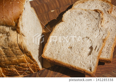 It is a slice of bread placed on a wooden cutting board. It is a slice of bread placed on a wooden cutting board. 141285338
