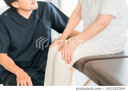 Male physical therapists and osteopaths listen to the knee pain concerns of senior women. 141285364