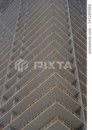Modern concrete skyscraper under construction with yellow safety barriers and copy space Modern concrete skyscraper under construction with yellow safety barriers and copy space 141285868
