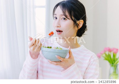 A young woman eating a salad 141285896