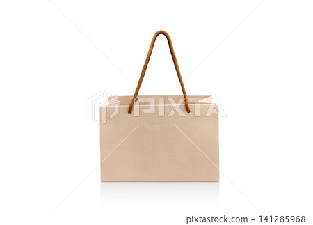 A small paper shopping bag is placed on a white background. A small paper shopping bag is placed on a white background. 141285968