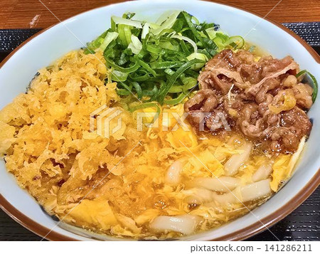 Warm udon noodles topped with pork, egg, and tempura flakes. Warm udon noodles topped with pork, egg, and tempura flakes. 141286211