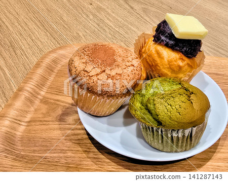 Three muffins on a white plate (plain, matcha, and red bean paste and butter) Three muffins on a white plate (plain, matcha, and red bean paste and butter) 141287143
