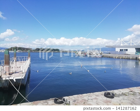 A fishing port scene with a clear blue sky and calm sea. 141287162