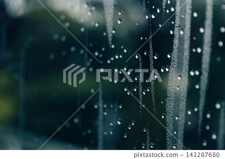 raindrops during raining in the rainy day outside window glass with a blurred background with water droplets flowing down the surface raindrops during raining in the rainy day outside window glass with a blurred background with water droplets flowing down the surface 141287680