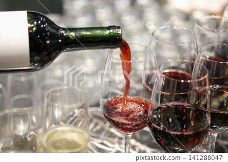 pouring wine in many glasses for dinner party, shot with narrow focus. pouring wine in many glasses for dinner party, shot with narrow focus. 141288047