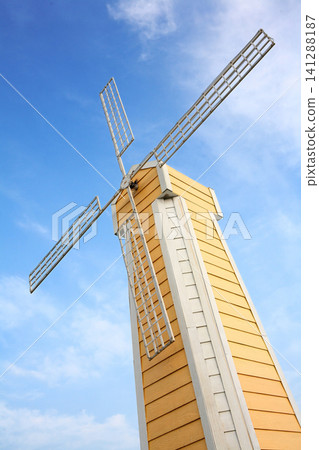 a tall vivid yellow windmill building with cloudy blue sky a tall vivid yellow windmill building with cloudy blue sky 141288187