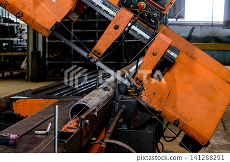 orange colored industrial cutting machine in working processed doing cutting a steel pipe in factory 141288291