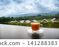 hot Thai's style milk tea in a cup with mountain view when a raining is coming from somewhere faraway 141288383