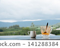 hot Thai's style milk tea in a cup with mountain view when a raining is coming from somewhere faraway 141288384